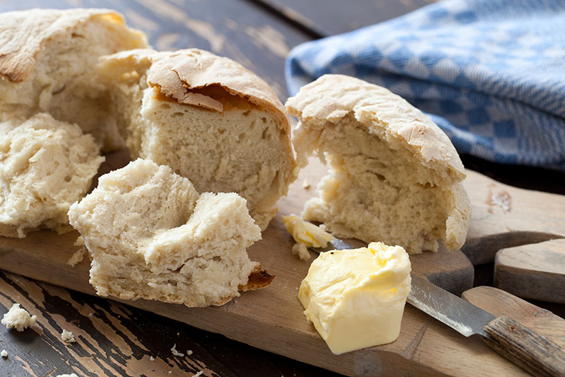 Stukken brood op een plank met boter en een mes